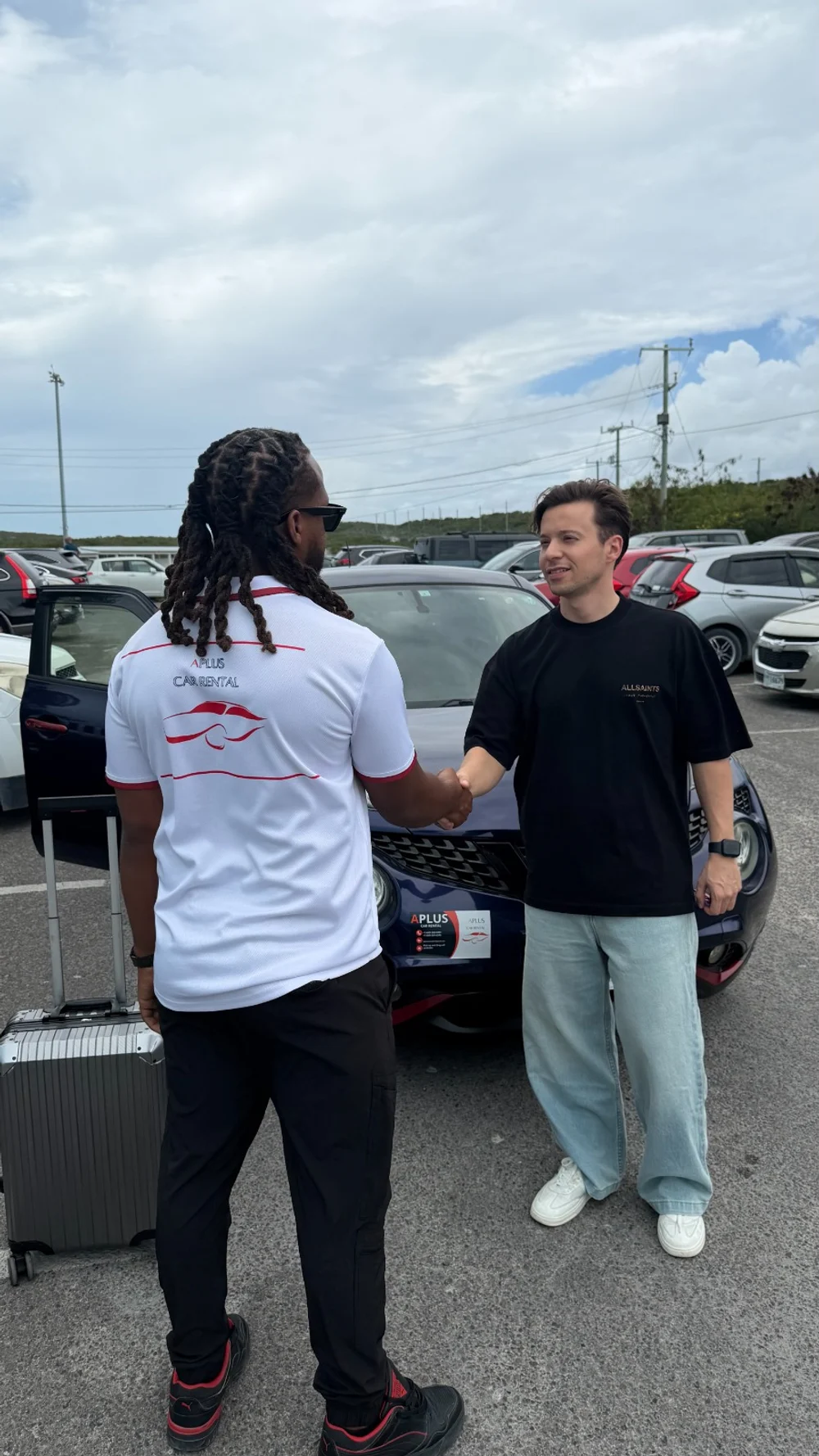 Aplus team member greeting a customer beside a rental car